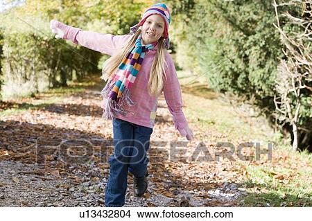 Picture - Young girl outdoors running on path smiling (selective focus). Fotosearch