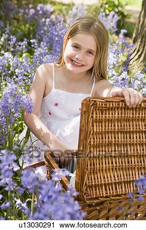 Young girl sitting outdoors with picnic basket smiling View Large Photo Image Stock Image - Young girl sitting outdoors with picnic basket smiling. Fotosearch