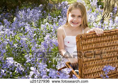 Young girl sitting outdoors with picnic basket smiling View Large Photo Image Stock Photograph - Young girl sitting outdoors with picnic basket smiling. Fotosearch