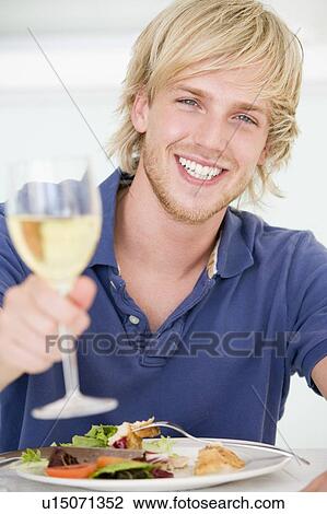 Stock Image - Young Man Enjoying meal, mealtime With A Glass Of Wine. Fotosearch