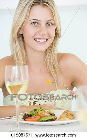 Stock Image - Young Woman Enjoying meal, mealtime With A Glass Of Wine. Fotosearch