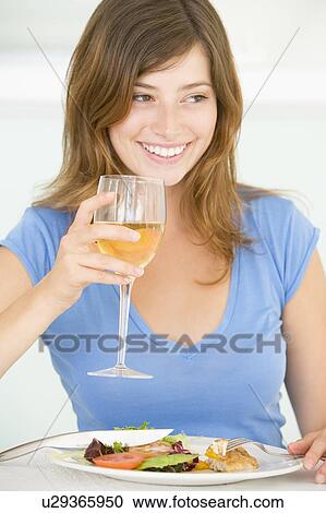 Stock Image - Young Woman Enjoying meal, mealtime With A Glass Of Wine. Fotosearch
