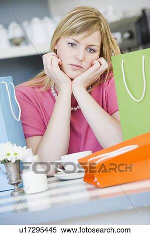 Young woman sitting at a table taking a break from shopping and drinking tea View Large Photo Image Stock Photography - Young woman sitting at a table taking a break from shopping and drinking tea. Fotosearch