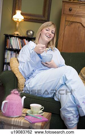 Young woman sitting at home eating a sweet treat View Large Photo Image Stock Image - Young woman sitting at home eating a sweet treat. Fotosearch