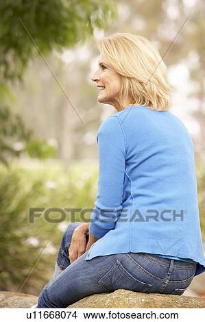 Picture - Back View Of Senior Woman Sitting On Wall. Fotosearch