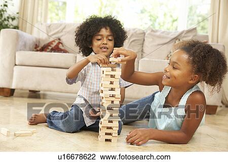 Stock Image - Brother And Sister Playing Game At Home. Fotosearch