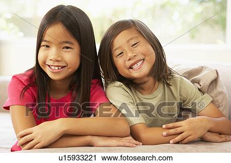 Stock Image - Brother And Sister Relaxing On Sofa At Home. Fotosearch