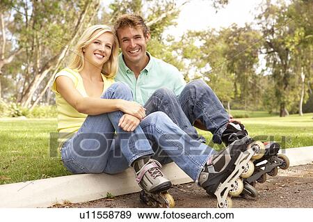 Couple Putting On In Line Skates In Park View Large Photo Image Stock Photo - Couple Putting On In Line Skates In Park. Fotosearch