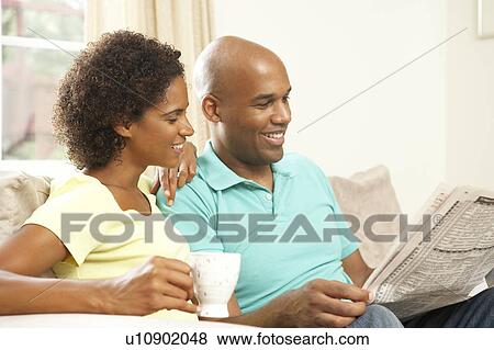 Stock Photo - Couple Relaxing At Home With Newspaper. Fotosearch