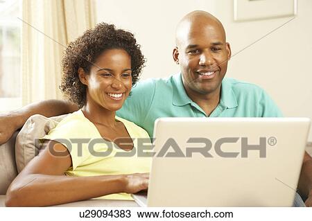 Stock Image - Couple Using Laptop At Home. Fotosearch