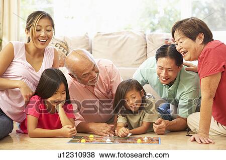 Stock Photo - Extended Family Group Playing Board Game At Home. Fotosearch