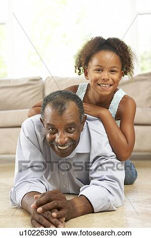 Stock Image - Grandfather And Granddaughter Playing Together At Home. Fotosearch