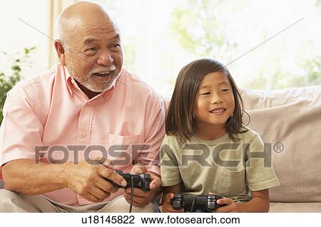 Stock Image - Grandfather And Granddaughter Playing Computer Game At Home. Fotosearch