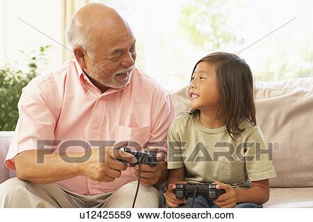 Stock Photo - Grandfather And Granddaughter Playing Computer Game At Home. Fotosearch