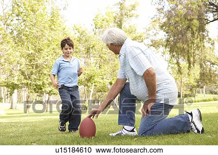 Stock Image - Grandfather And Grandson Playing American Football Together. Fotosearch