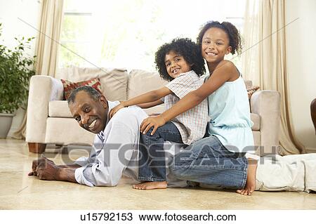 Stock Image - Grandfather Playing With Grandchildren At Home. Fotosearch