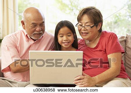 Stock Photo - Grandparents And Grandaughter Using Laptop Computer At Home. Fotosearch