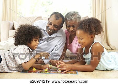 Stock Photo - Grandparents Playing Board Game At Home With Grandchildren. Fotosearch