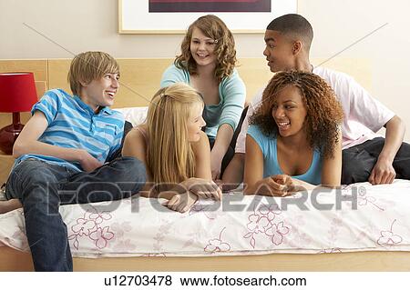 Stock Photo - Group Of Five Teenage Friends Hanging Out In Bedroom. Fotosearch