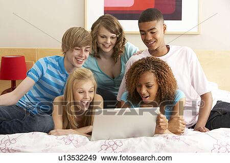 Stock Photo - Group Of Five Teenage Using Laptop In Bedroom. Fotosearch