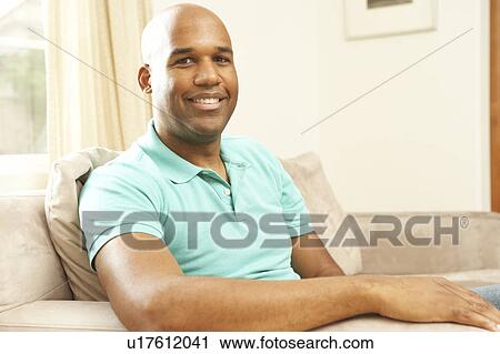 Stock Image - Man Relaxing On Sofa At Home. Fotosearch