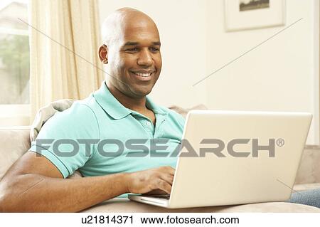 Stock Image - Man Using Laptop At Home. Fotosearch