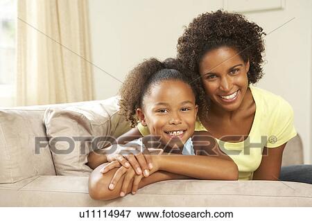 Stock Photo - Mother And Daughter Relaxing On Sofa At Home. Fotosearch