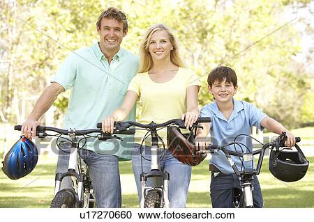 Stock Image - Parents And Son On Cycle Ride In Park. Fotosearch