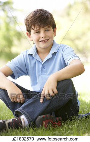 Stock Image - Portrait Of Young Boy Sitting In Park. Fotosearch