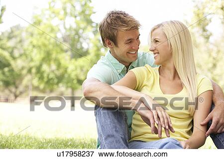 Portrait Of Young Couple Sitting In Park View Large Photo Image Stock Photo - Portrait Of Young Couple Sitting In Park. Fotosearch