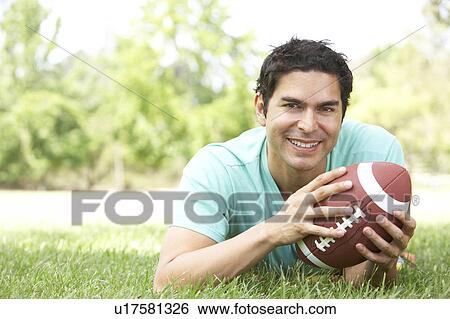 Stock Photograph - Portrait Of Young Man In Park With American Football. Fotosearch