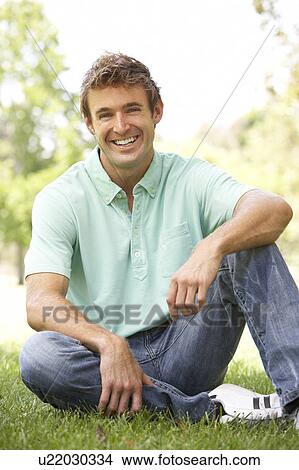 Picture - Portrait Of Young Man Sitting In Park. Fotosearch