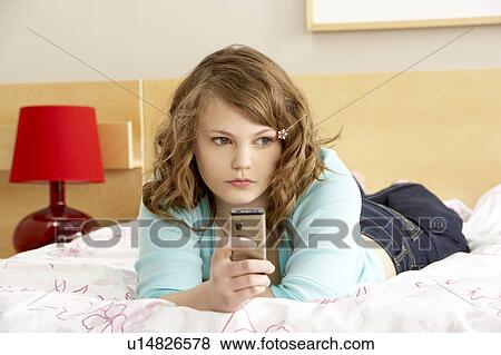 Stock Photo - Sad Teenage Girl In Bedroom With Mobile Phone. Fotosearch