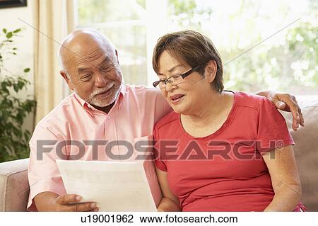 Stock Image - Senior Couple Discussing Document At Home. Fotosearch