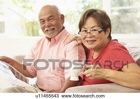 Stock Image - Senior Couple Reading Newspaper At Home. Fotosearch