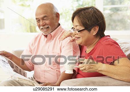 Stock Image - Senior Couple Reading Newspaper At Home. Fotosearch