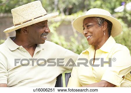Stock Image - Senior Couple Relaxing In Garden Together. Fotosearch