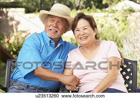 Stock Image - Senior Couple Relaxing In Garden Together. Fotosearch