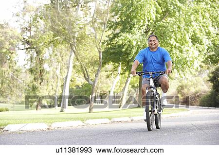Stock Image - Senior Man Cycling In Park. Fotosearch