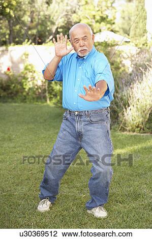 Stock Image - Senior Man Doing Tai Chi In Garden. Fotosearch