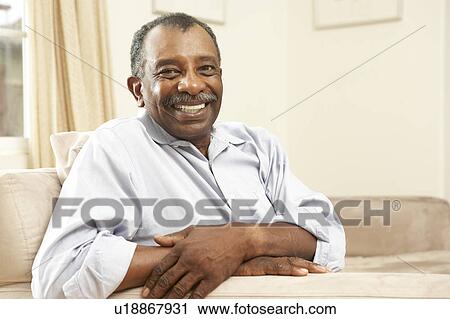 Stock Image - Senior Man Relaxing In Chair At Home. Fotosearch