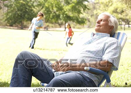 Senior Man Relaxing In Park With Grandchildren In Background View Large Photo Image Stock Photo - Senior Man Relaxing In Park With Grandchildren In Background. Fotosearch
