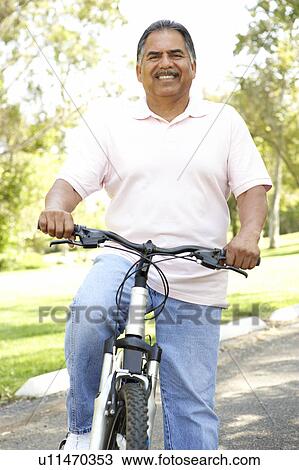 Stock Image - Senior Man Riding Bike In Park. Fotosearch