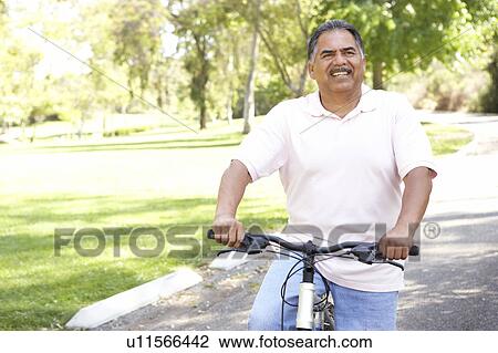 Stock Image - Senior Man Riding Bike In Park. Fotosearch