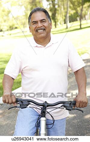 Stock Image - Senior Man Riding Bike In Park. Fotosearch
