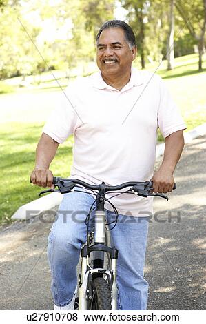 Stock Photo - Senior Man Riding Bike In Park. Fotosearch