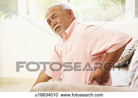 Stock Image - Senior Man Suffering From Back Pain At Home. Fotosearch