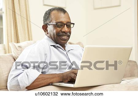 Stock Image - Senior Man Using Laptop At Home. Fotosearch
