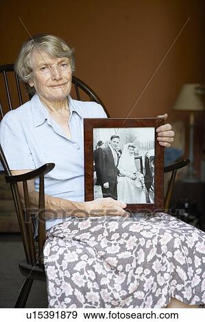 Stock Photo - Senior Woman At Home Looking At Old Wedding Photo. Fotosearch