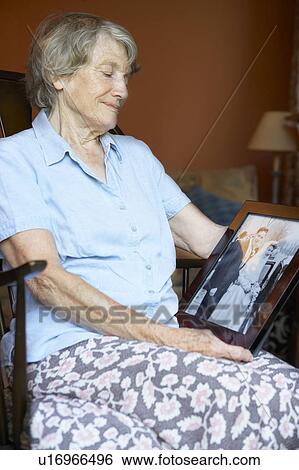 Stock Photograph - Senior Woman At Home Looking At Old Wedding Photo. Fotosearch